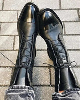 Front view of lace-up leather ankle boots on a plain background