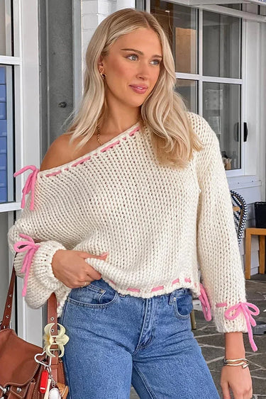 Front view of an asymmetrical jumper with tie detail in white