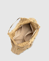 Styled shot of the beaded straw hobo bag carried by hand against a neutral background