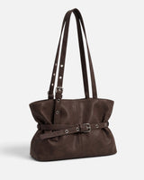 Close-up of the buckle and metal eyelet belt detail on the front of the tote bag