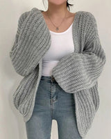 Styled shot of chunky knit cardigan layered over a simple dress