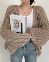 Oversized chunky knit cardigan with balloon sleeves worn open over a casual outfit