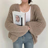Oversized chunky knit cardigan with balloon sleeves worn open over a casual outfit