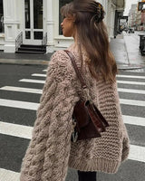 Front view of women's cable-knit cardigan in a relaxed hip-length silhouette