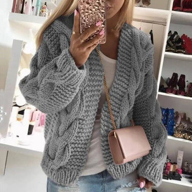 Model wearing open-front cable knit cardigan over a simple top