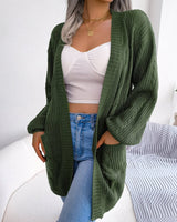 Full-length view of model wearing open-front chunky knit cardigan over simple top