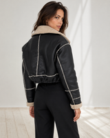 Side view showing the cropped waist-length silhouette and exposed seam detailing