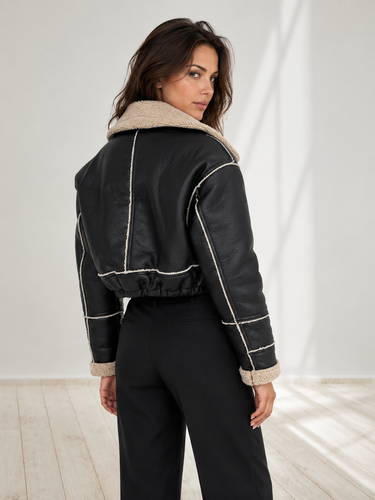 Side view showing the cropped waist-length silhouette and exposed seam detailing