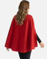 Three-quarter view of the cape coat layered over a knit, showing the overall shape