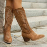 Knee-high western boot with embroidered stitching along the shaft and a stacked block heel