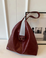 Faux leather shoulder bag shown from above, displaying minimal detailing and strap