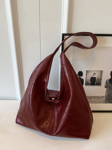 Faux leather shoulder bag shown from above, displaying minimal detailing and strap