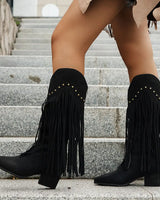 Pair of fringed cowboy boots standing upright on a flat surface