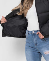 Model wearing the hooded puffer jacket from the front in a street setting