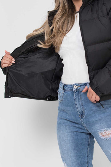 Model wearing the hooded puffer jacket from the front in a street setting