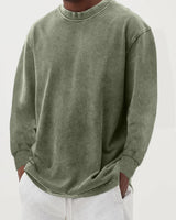 Men's chunky knit jumper styled with straight-leg trousers, three-quarter view