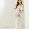 Front view of a white off-shoulder long-sleeve maternity dress with a flowing skirt