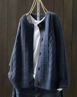 Detail shot of ribbed cuffs and button closure on cable knit cardigan