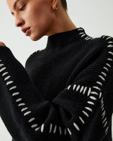Side view showing dropped shoulders and hip-length hem of the knit jumper