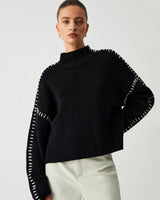 Front view of an oversized knit jumper with mock neck and contrast-stitch seams