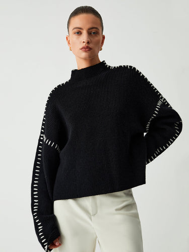 Front view of an oversized knit jumper with mock neck and contrast-stitch seams