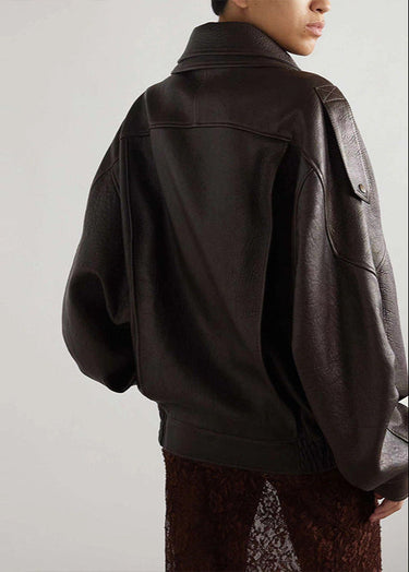 Close-up of asymmetric zip and snap button closure on a leather bomber jacket
