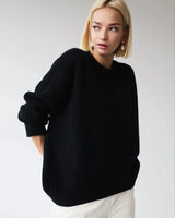 Model wearing an oversized sweater in emerald with straight-leg trousers