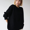 Model wearing an oversized sweater in emerald with straight-leg trousers
