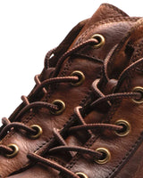Men's leather boot styled in a street setting, three-quarter view