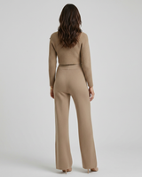 Side view showing the wide-leg trouser silhouette and fitted long-sleeve top