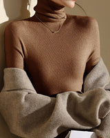 Model wearing the roll neck top layered under a tailored jacket