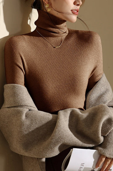 Model wearing the roll neck top layered under a tailored jacket