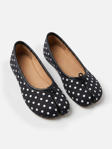 Side profile of polka-dot ballet flat showing flat sole and split toe