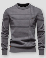 Man wearing a textured crew neck jumper with raised knit detailing on the front