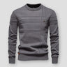 Man wearing a textured crew neck jumper with raised knit detailing on the front