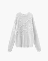Detail shot of the ribbed cuff and sleeve on the white knit sweater