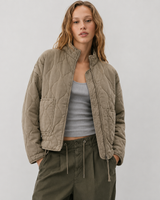 Full-length view of quilted jacket worn over a knit jumper