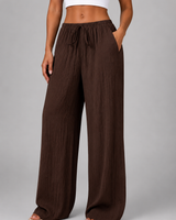 Model wearing wide leg crinkle trousers, turned to the side