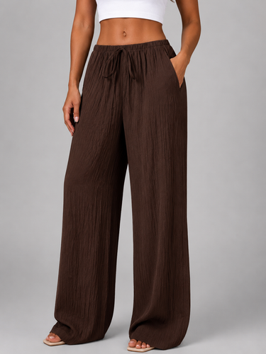 Model wearing wide leg crinkle trousers, turned to the side
